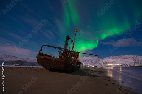 Aurora borealis over an old abandoned ship on a March night. Teriberka. Murmansk region, Russia