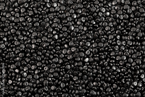 Texture of black polyethylene granules, close-up. Masterbatch or virgin PE pellets dyed with carbon black pigment. Granulated plastic polymer