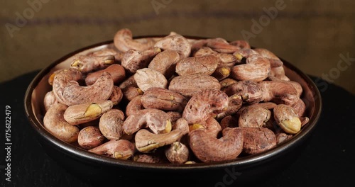 Roasted Salted Nut Heap Snack Cashew in Shell Rotating Background in Ceramic Bowl over Burlap Wall