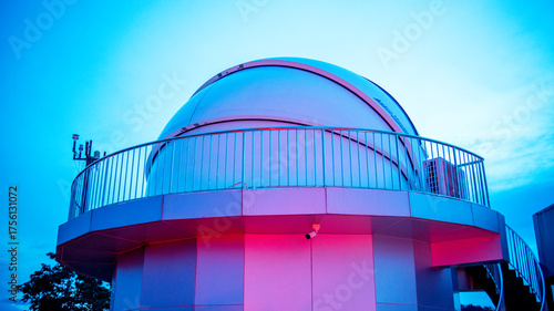 Futuristic astronomical observatory dome at twilight featuring vibrant blue and pink lighting that enhances its modern architectural design, Themes related to space exploration science and technology.