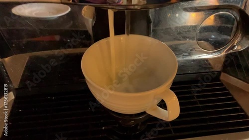 Pouring milk and coffee in a tea cup.