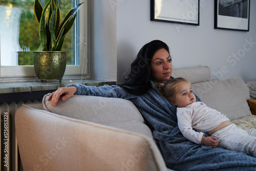 Woman and daughter relaxing on sofa at home