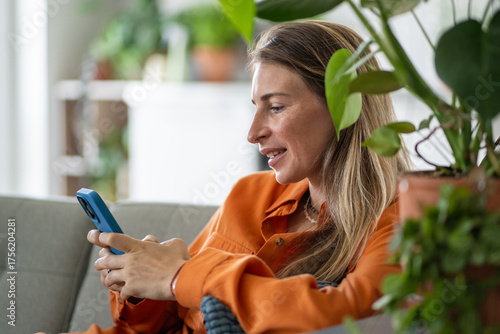 Bilde på lerret Positive middle-age woman actively texting message or typing online comment intently concentrated on phone