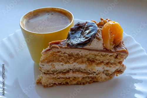 Dessert with fresh fruits on a plate and a cup of coffee. Cake with dried apricots, prunes and walnuts. Breakfast with morning espresso. A treat on a plate.