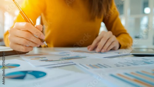 Person analyzing data and charts in a professional setting.
