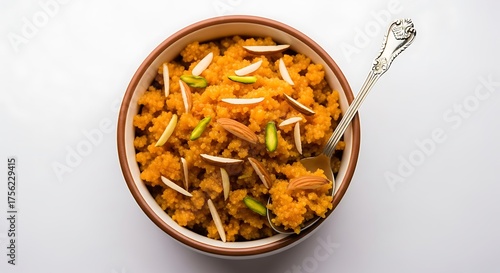 Closeup top view of a bowl of delicious moong dal halwa, a traditional indian sweet dessert, garnished with almonds and pistachios