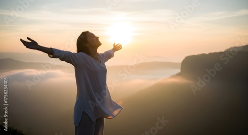 Woman standing on mountain with arms outstretched towards the sun, embracing nature and feeling free. Celebrating a spiritual connection with the world at sunrise, finding inner peace.