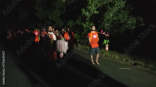 Nighttime footage of Kanwariya devotees dressed in saffron attire carrying decorated Kanwars Kawads during the sacred Shravan Somwar Sawan Monday pilgrimage in India. Illuminated by artificial lights