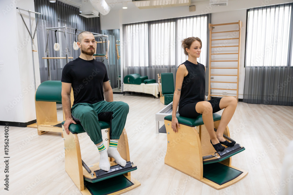 Fototapeta premium chair machine, Pilates exercises. exercises to strengthen body and stretch. practicing physical fitness exercises on Pilates machine. Reformer pilates machine for fitness workouts in gym studio