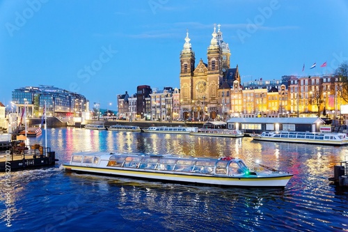 Photography A tour boat cruising on the canal near Amsterdam's Central Railway Station, with