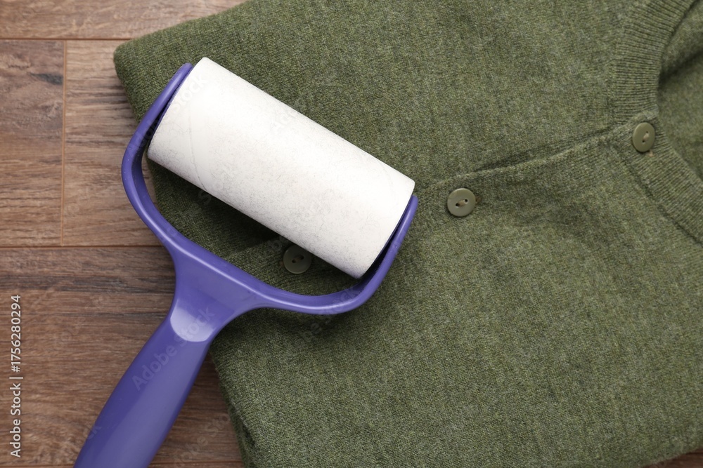 Obraz premium Sticky lint roller and shirt on wooden table, top view