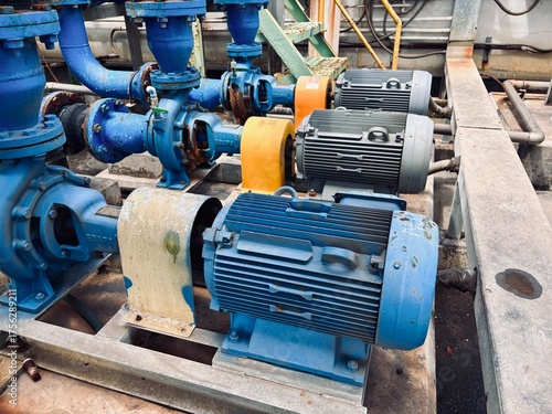 A row of blue industrial centrifugal pumps driven by electric motors, with connecting blue pipes and valves, showcasing heavy machinery for water or chemical fluid processing in a factory environment.