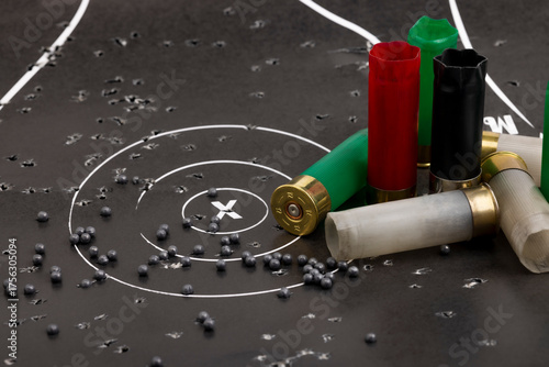 Quadro su tela Empty fired shotgun shell and lead pellets on bull eye paper target background