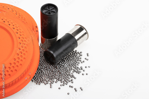 Clay flying target and Shotgun shell ammunition with lead pellets on white background , gun and shooting game