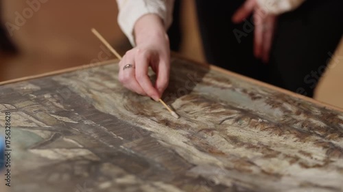 Top view. Restoration procedure of the painting. Restorer artist restore paint on picture. Close-up of elegant female hand. Cultural concept.