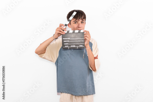 young casual dressed Generation Z influencer white male model teenage boy prepares to create and direct social media film reel with blank clapperboard slate. plain background studio setting