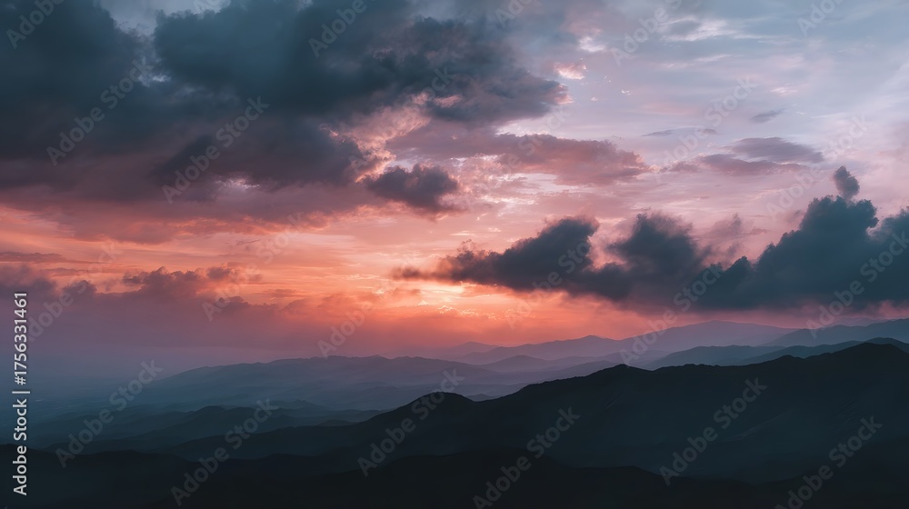 Obraz premium Dramatic sunset over layered mountain ranges with atmospheric clouds and a muted color palette