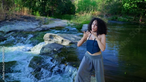 A Young Woman Experiencing Nature's Beauty by the Stream, Expressing Joy and Calmness Amidst Lush Greenery and Flowing Water