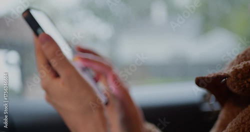 Close-up of hands using a smartphone inside car, tapping the touchscreen with ambient light and soft background. Technology, communication, mobile device, travel, modern lifestyle concepts.