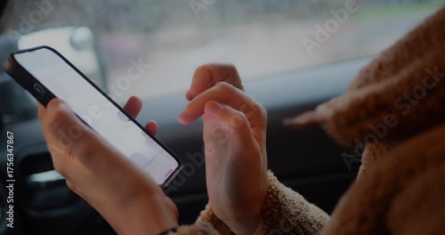 Close-up of hands scrolling right to left on a smartphone screen inside a car, focusing on touchscreen interaction, technology, mobile browsing, digital communication, and modern lifestyle on the move