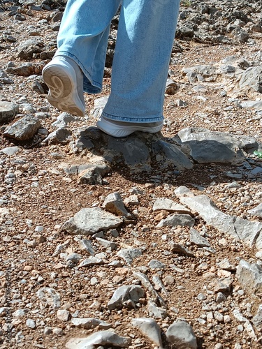 A woman walks along a path in a mountainous area with granite rocks