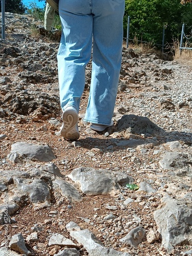A woman walks along a path in a mountainous area with granite rocks