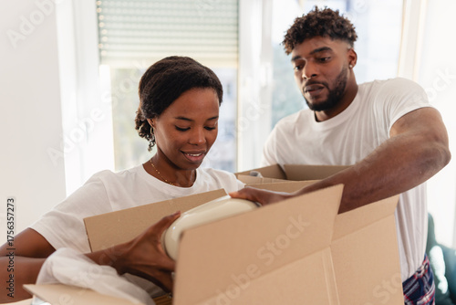 African American couple unpacking boxes together in their new home, organizing household items and enjoying the moving day process