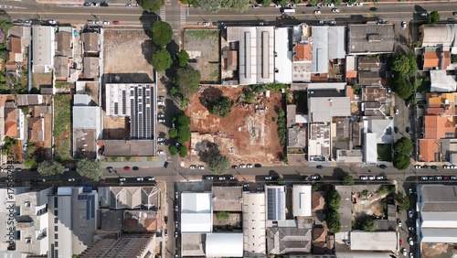 Aerial photo taken by drone showing an empty lot in the middle of an urban area surrounded by residential and commercial buildings. The image highlights city planning, street layout, and architectural