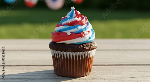Patriotic cupcake sits on wooden picnic table in sunny backyard, celebrating independence day with festive red, white, and blue frosting swirls.