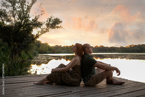 Couple enjoying a peaceful sunset on a wooden pier by the lake