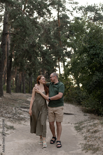 a couple walking through a pine forest hug and look at each other
