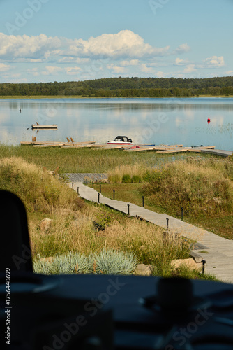 Calm Waters with a Scenic Dock Surrounded by Lush Greenery under a Beautiful Sky