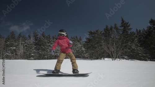 4K video of a woman snowboarding down a cold winter mountain on a sunny snowy day at Killington, Vermont, New England, USA. Thrill and excitement. 