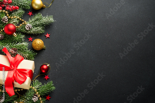 Black Christmas flat lay background. Holiday decorations with present box and Christmas tree on black with copy space.