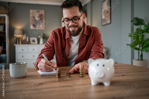 Photos Man calculating savings with coins and piggy bank