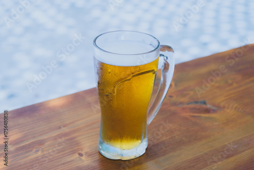 50 cl pint of beer served on wooden surface. Cold beer glass on wooden table. Refreshing golden beer in glass on wooden table. Full glass of lager beer on wooden table.