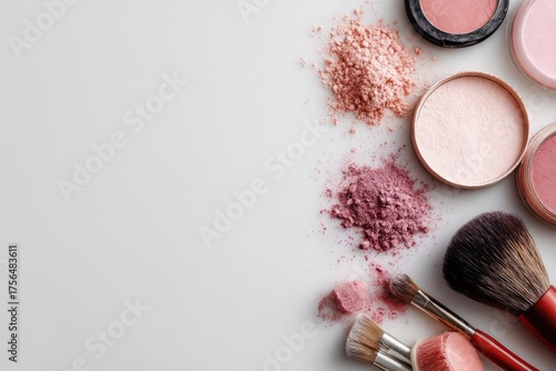 Flat lay of various makeup products including blush powder and brushes on a white background with copy space