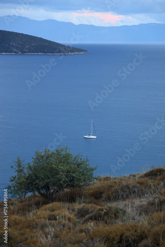 Aerial view of a sailboat anchored in the calm Aegean Sea at autumn sunset in the famous resort town of Bodrum.