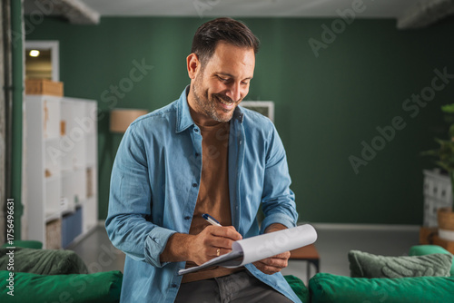 Man smiling checking list clipboard working from home office