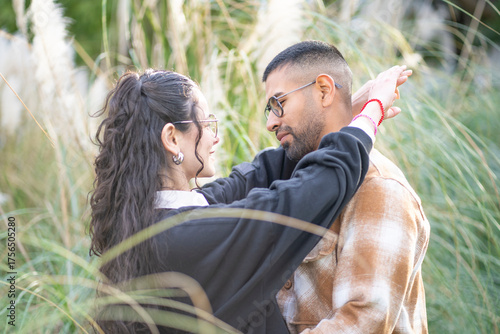Latin couple hugging in a park, looking into each other's eyes, about to kiss