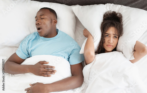 фотографія Snoring man sleeping with apnea and sleepless woman, angry wife unable to get to sleep