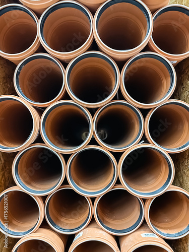 A vertical stack of orange PVC pipes bundled in a wooden crate, showcasing durable plumbing materials for water supply, drainage, and construction projects in industrial settings.