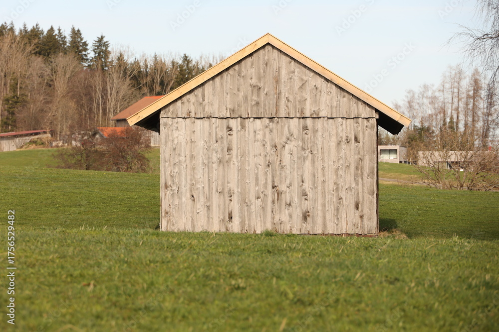 Obraz premium A small, old wooden building sits in a grassy field