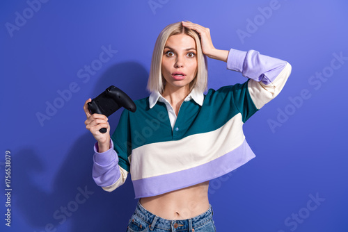 Young stylish woman holding a gaming controller with a surprised expression in a casual colorful outfit