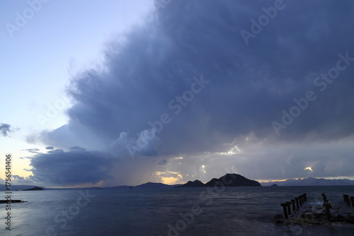 Heavy, storm clouds over the ocean, herald the arrival of a storm. Beautifully illuminated dark clouds and reflections in the ocean water