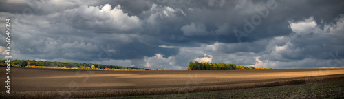 An epic panorama of agricultural crops in central Ukraine.Autumn fieldwork. An endless horizon with engulfing clouds.
