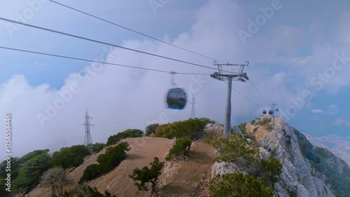 Time lapse: gondola cabins moving across the steep, rocky peak of Mount Babadag while clouds swirl around in Mugla, Turkey - wide angle. Timelapse, scenic aerial transit and mountain travel