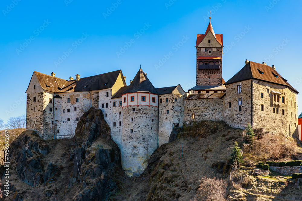 Naklejka premium Historic medieval castle on rocky hill under clear blue sky
