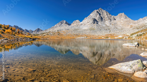 Crystal clear lake perfectly mirrors jagged, snow-dusted peaks under a vibrant blue sky