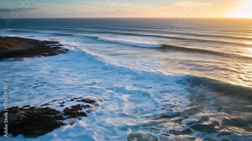 Aerial View of Ocean Waves Crashing on a Rocky Coast at Sunset.